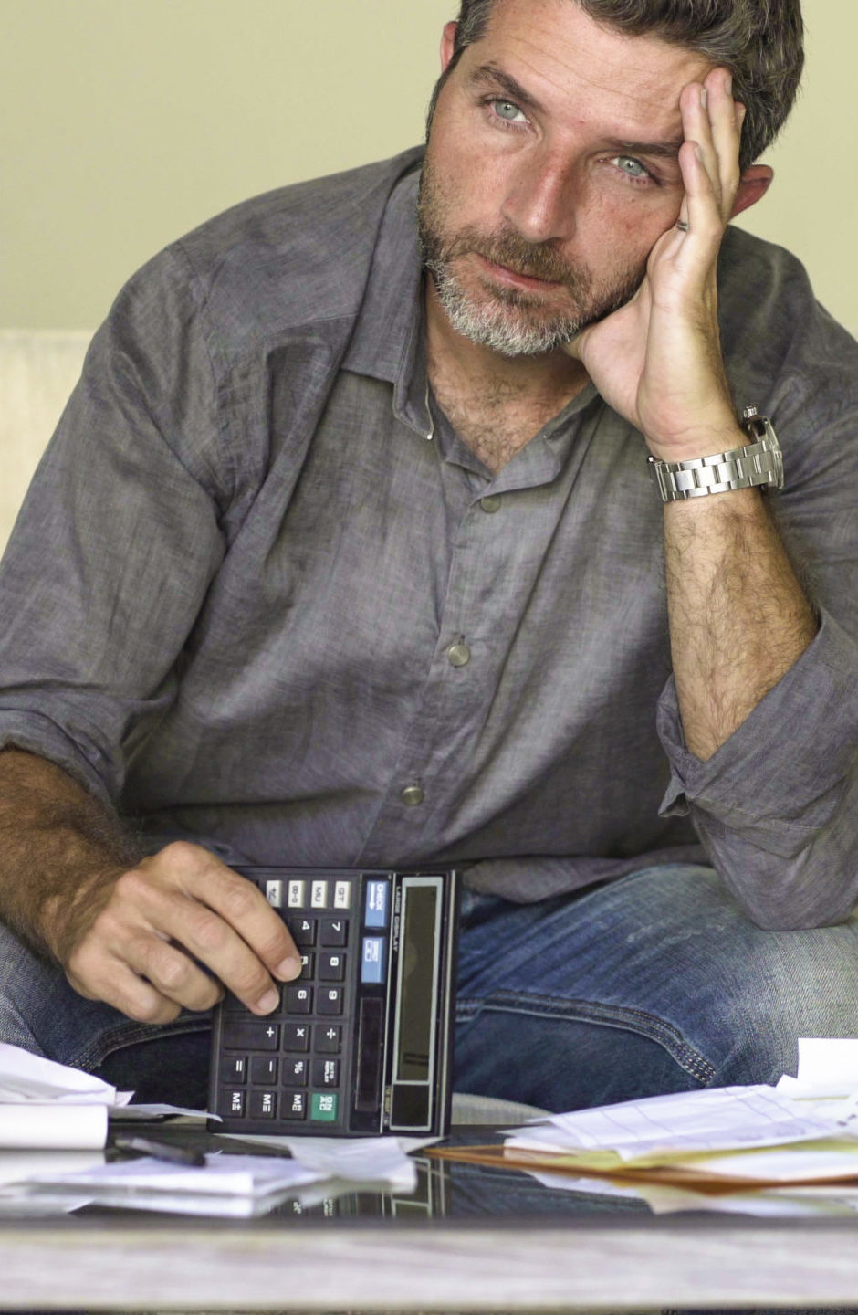stressed and desperate man at home living room couch doing domestic accounting with paperwork and calculator feeling overwhelmed and worried suffering financial crisis young stressed and desperate man at home living room couch doing domestic accounting with paperwork and calculator feeling overwhelmed and worried suffering financial crisis debt and ruin